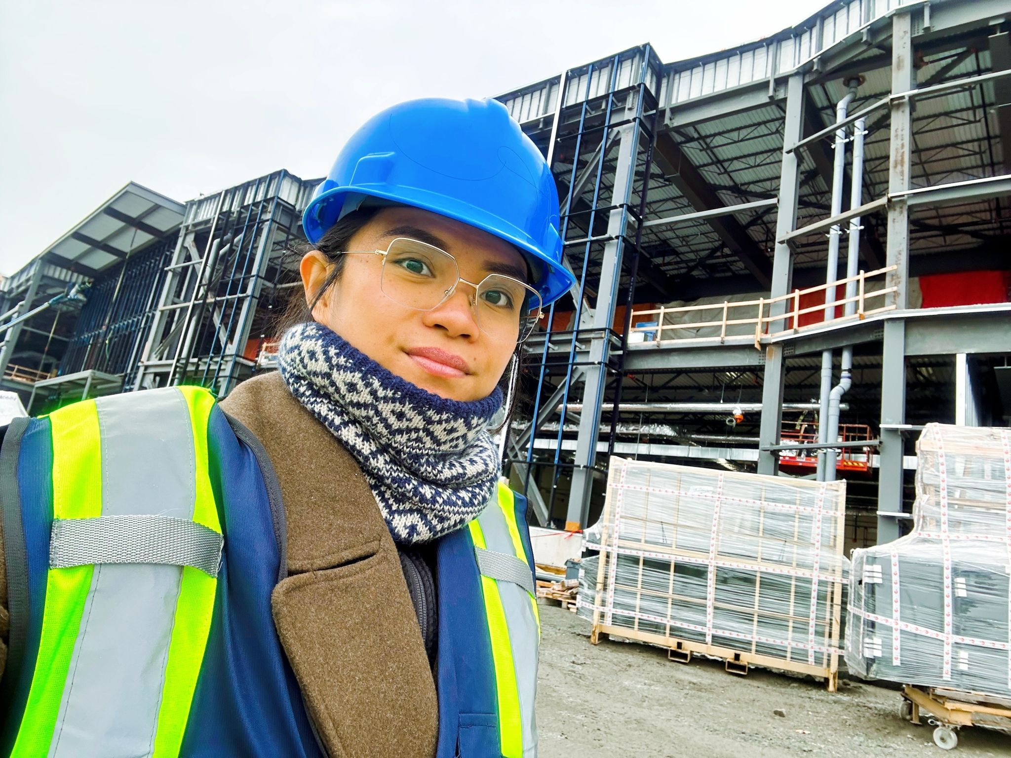 Eliana wearing a hardhat and high-viz vest on a jobsite.