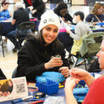 A woman wearing a Neil Squire toque adapts a toy.