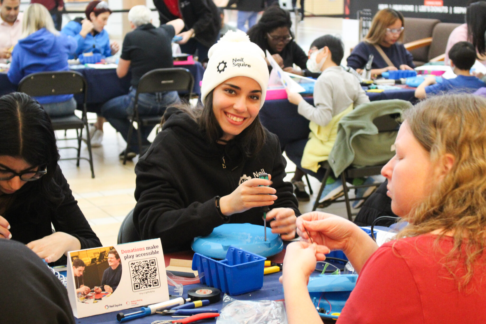 A woman wearing a Neil Squire toque adapts a toy.