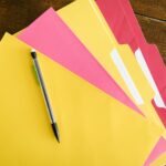 Folders on a table with a pencil on top.