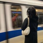 A woman wearing headphones watches the SkyTrain.