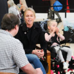 Grant Hardy interviewing Carey, Evie's mother, with Evie beside her in her wheelchair.