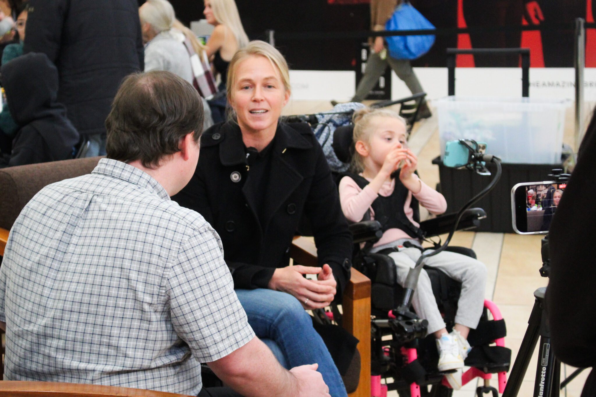 Grant Hardy interviewing Carey, Evie's mother, with Evie beside her in her wheelchair.