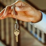 A man holds a house key on a chain.