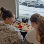 Volunteers build a switch at the Cranbrook build next to a window, which shows snow on the ground outside.