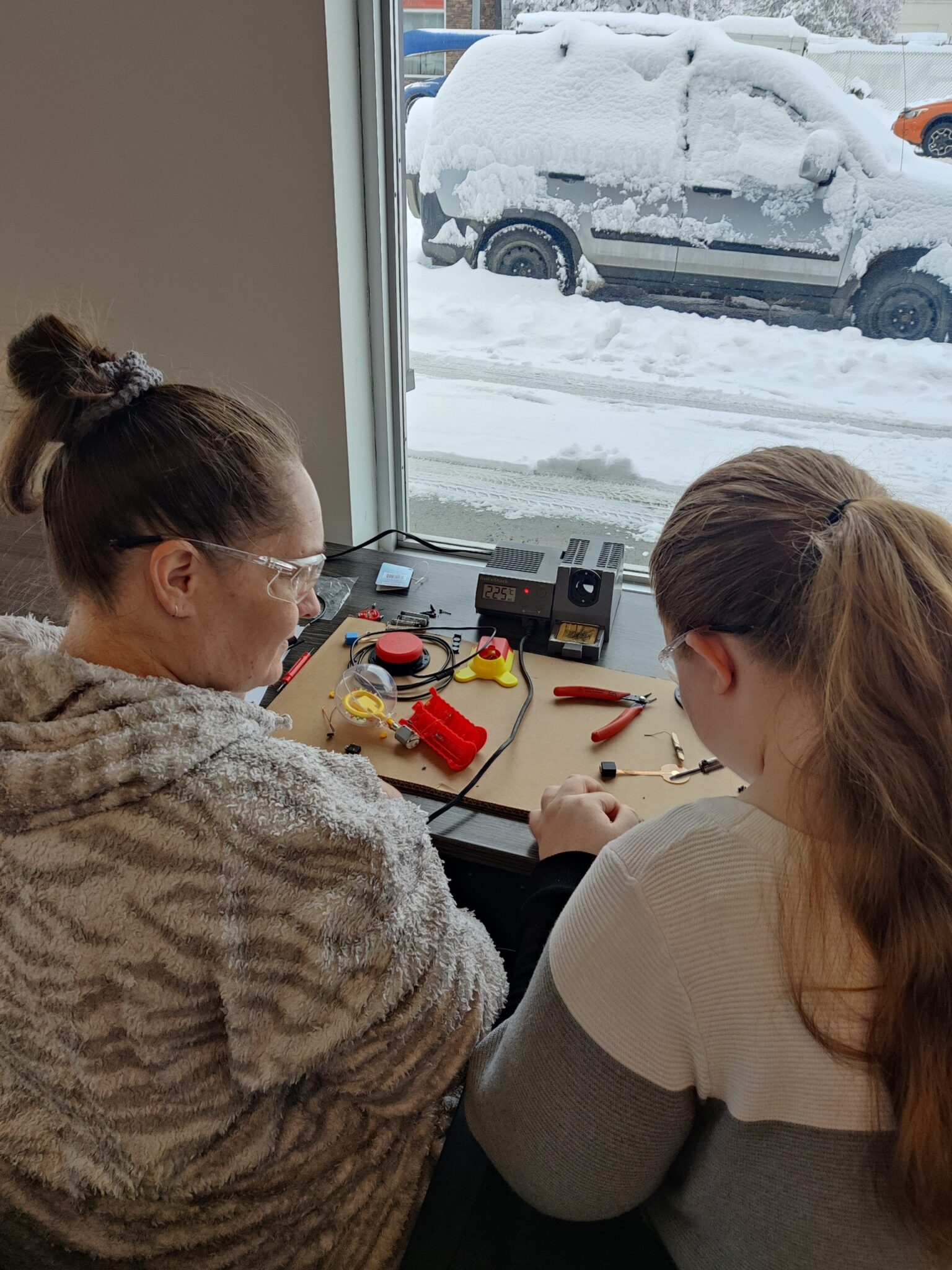 Volunteers build a switch at the Cranbrook build next to a window, which shows snow on the ground outside.