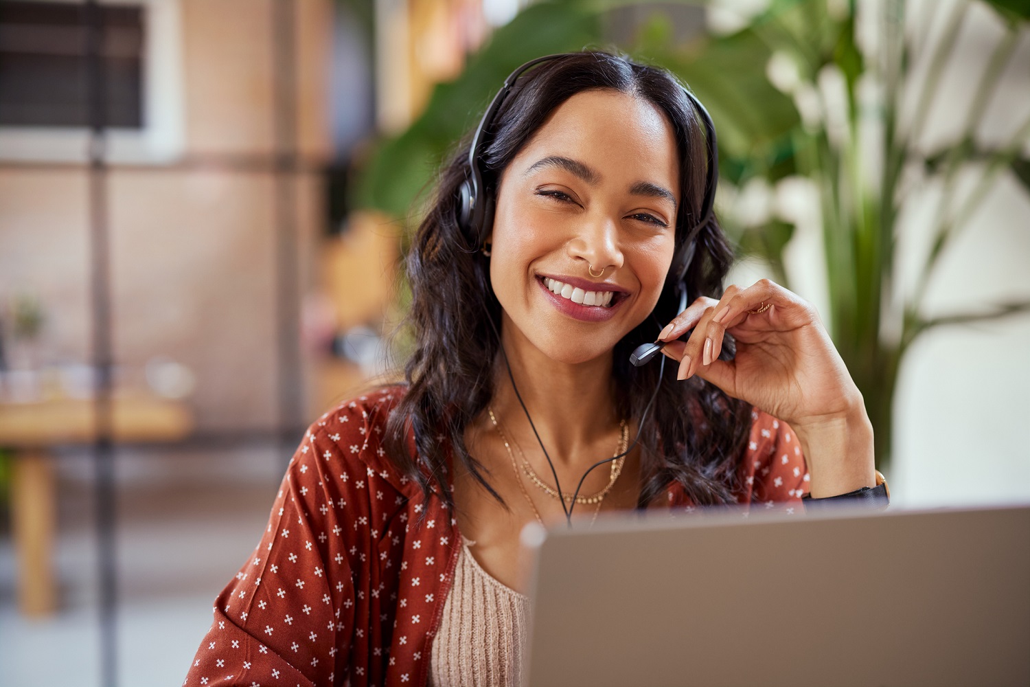 A woman wearing a headset uses a laptop.