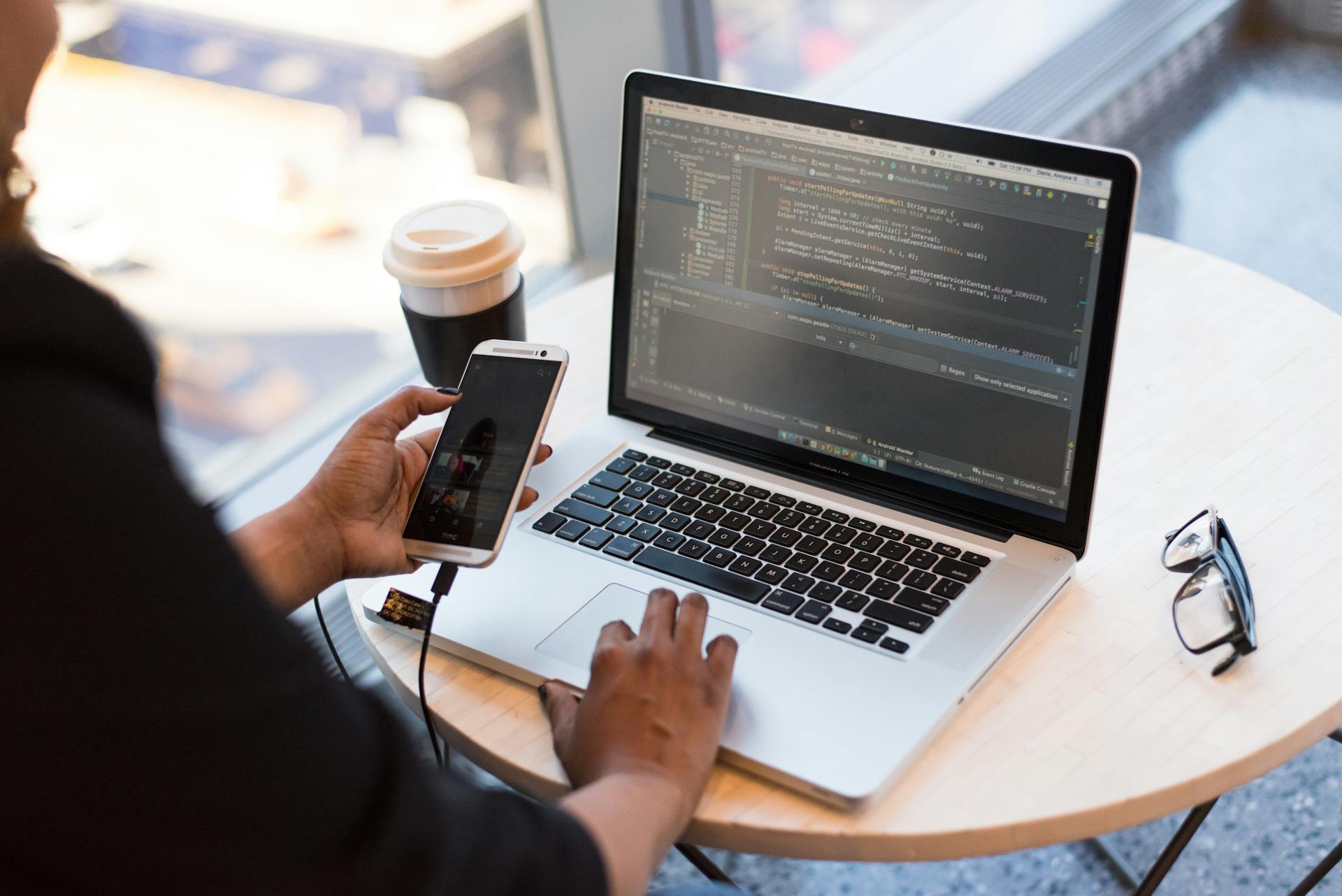 A woman goes on the phone while writing code on her laptop