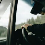 A person has their hand on the steering wheel as they drive.