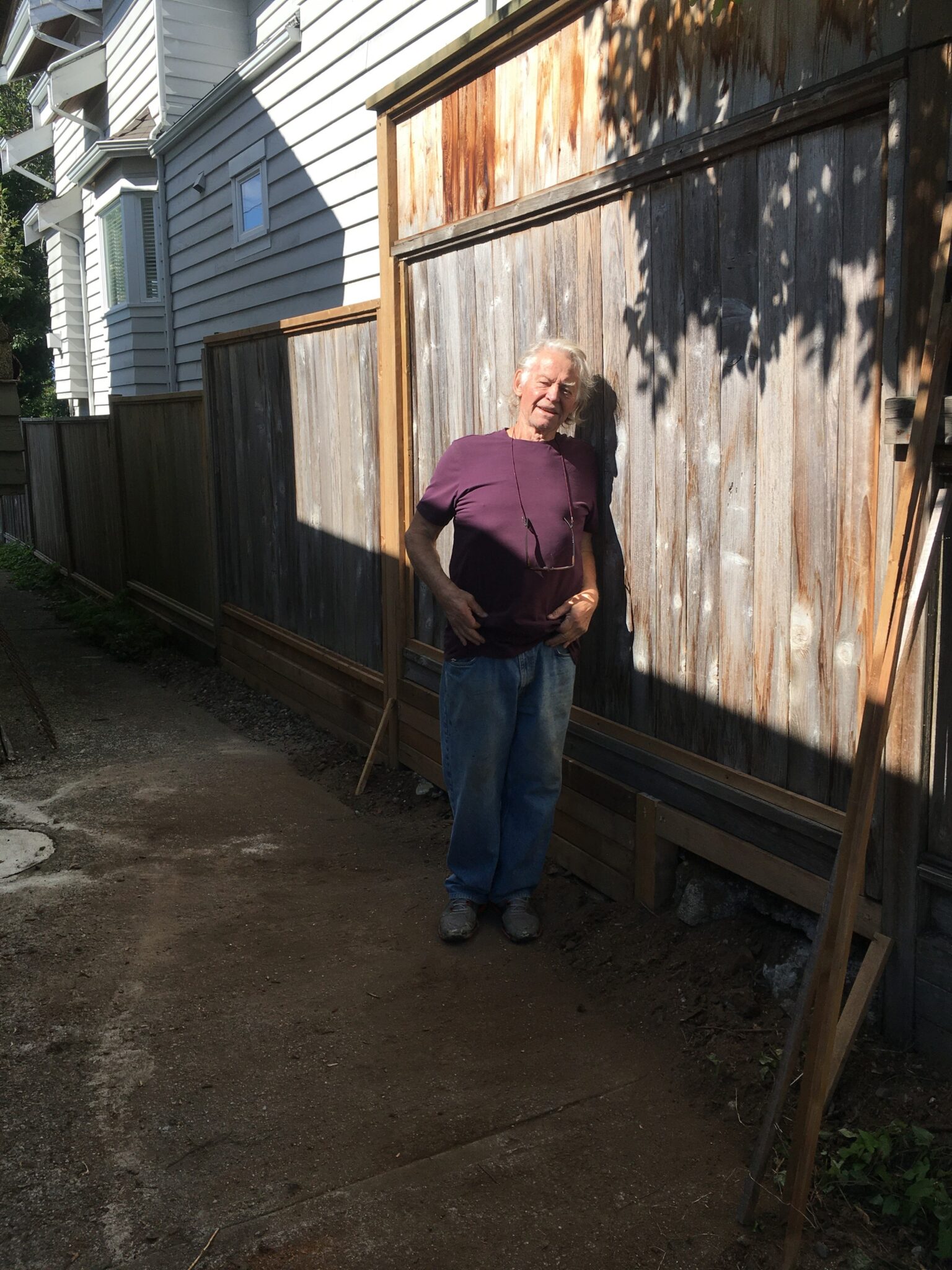 Anthony standing in front of a wooden fence.