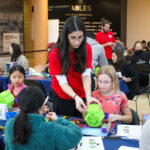 Didi helps a child adapt a bubble blower toy at a build event.