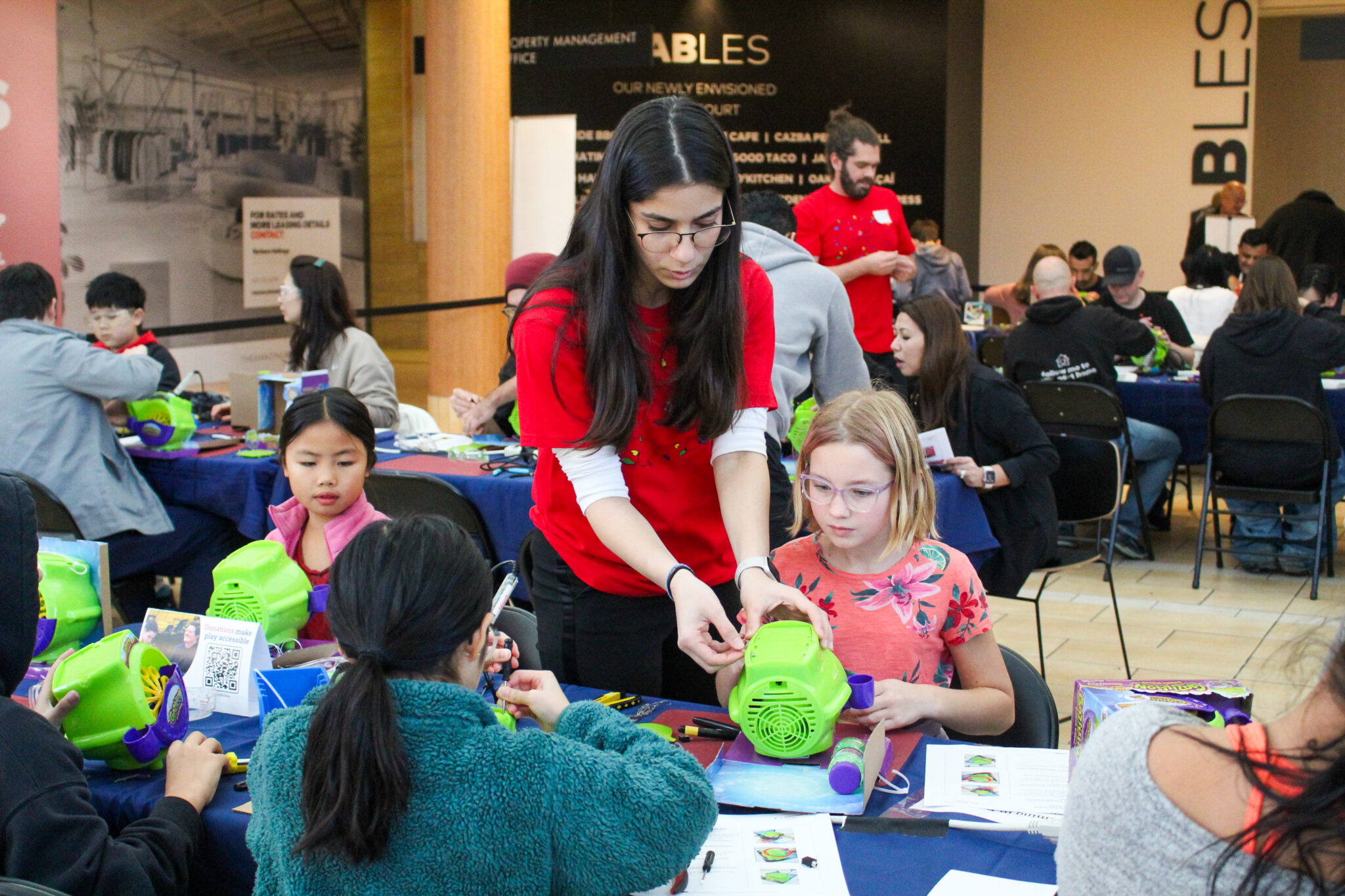 Didi helps a child adapt a bubble blower toy at a build event.