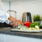 A chef cuts vegetables in a kitchen.