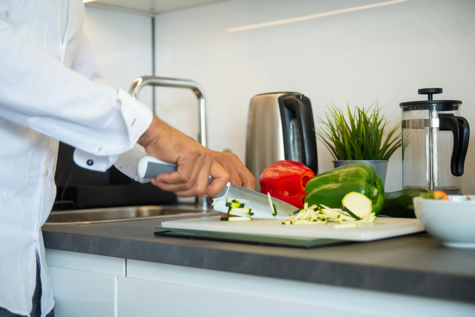 A chef cuts vegetables in a kitchen.